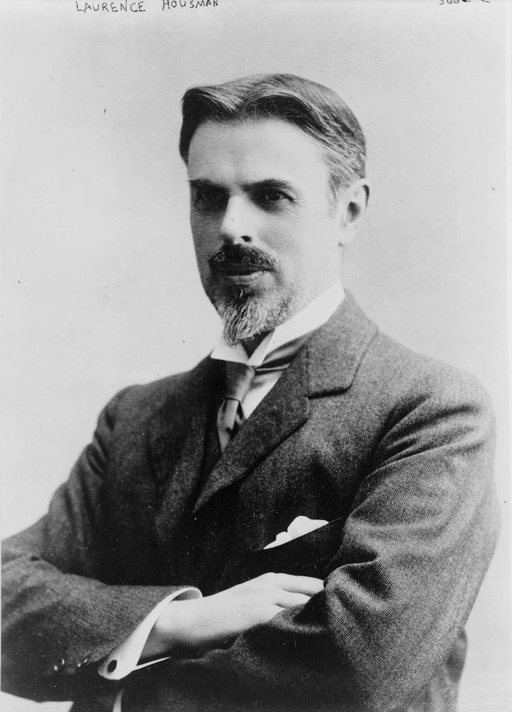 A black and white half-length photographic portrait of Laurence Housman, turned to the right with his arms crossed.